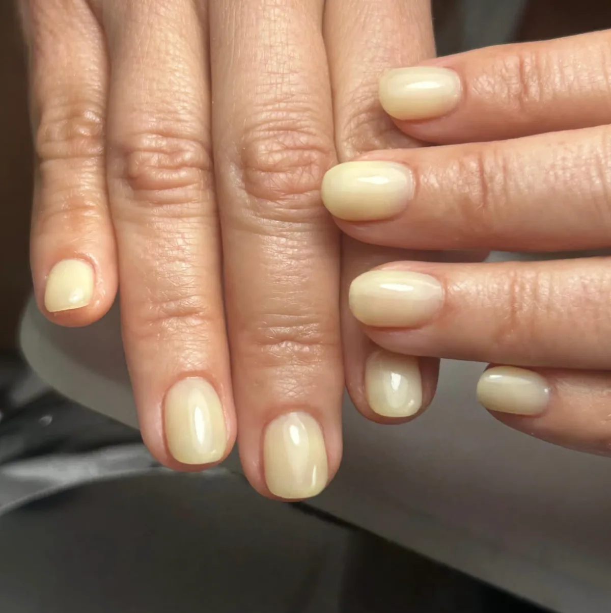Manicura corta color crema con acabado brillante.
