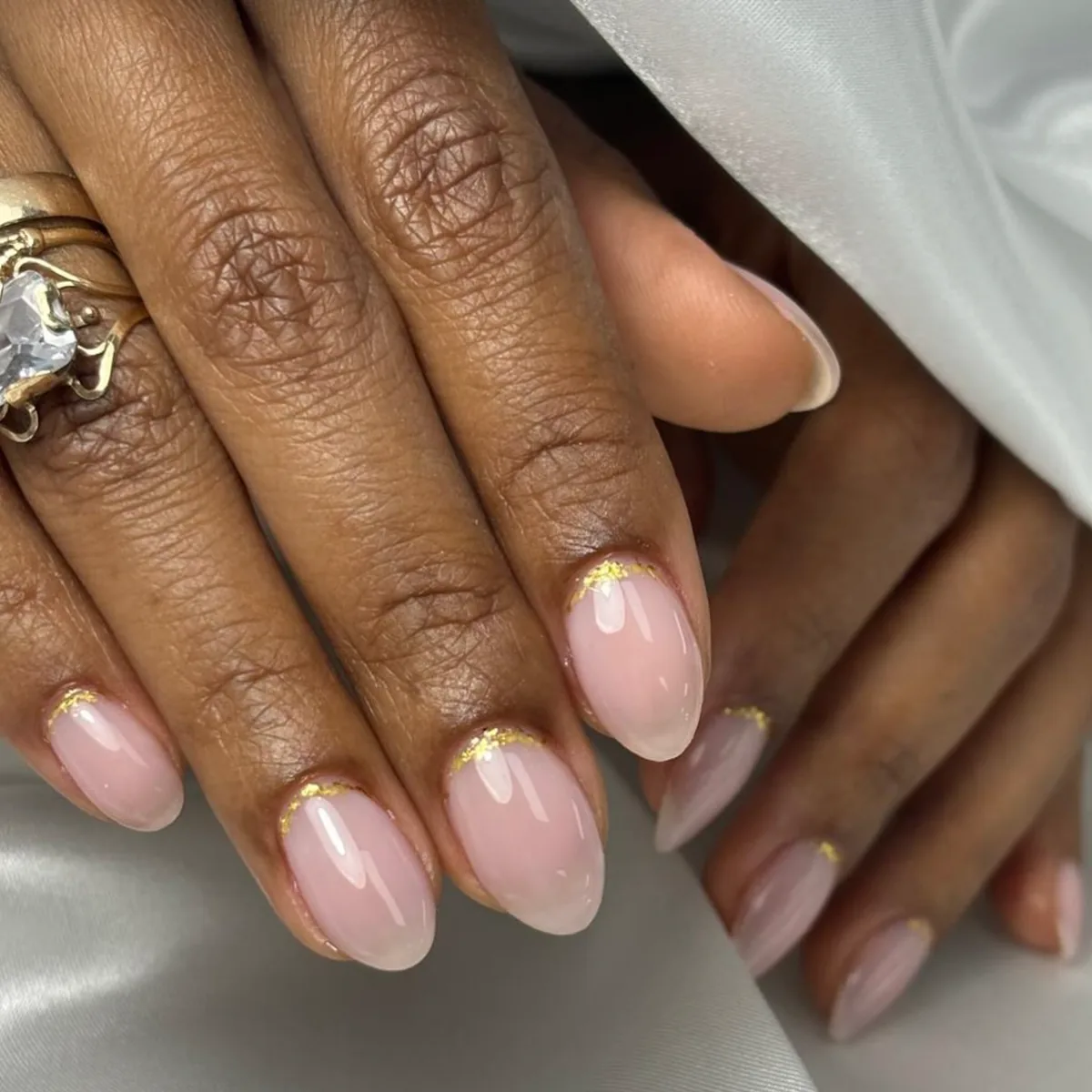Uñas rosa suave con detalle dorado cerca de la cutícula.