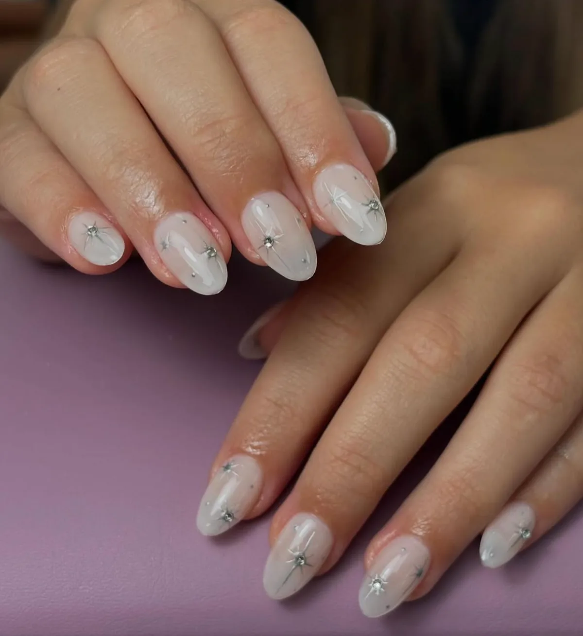 Uñas blancas lechosas con detalles de estrellas brillantes.