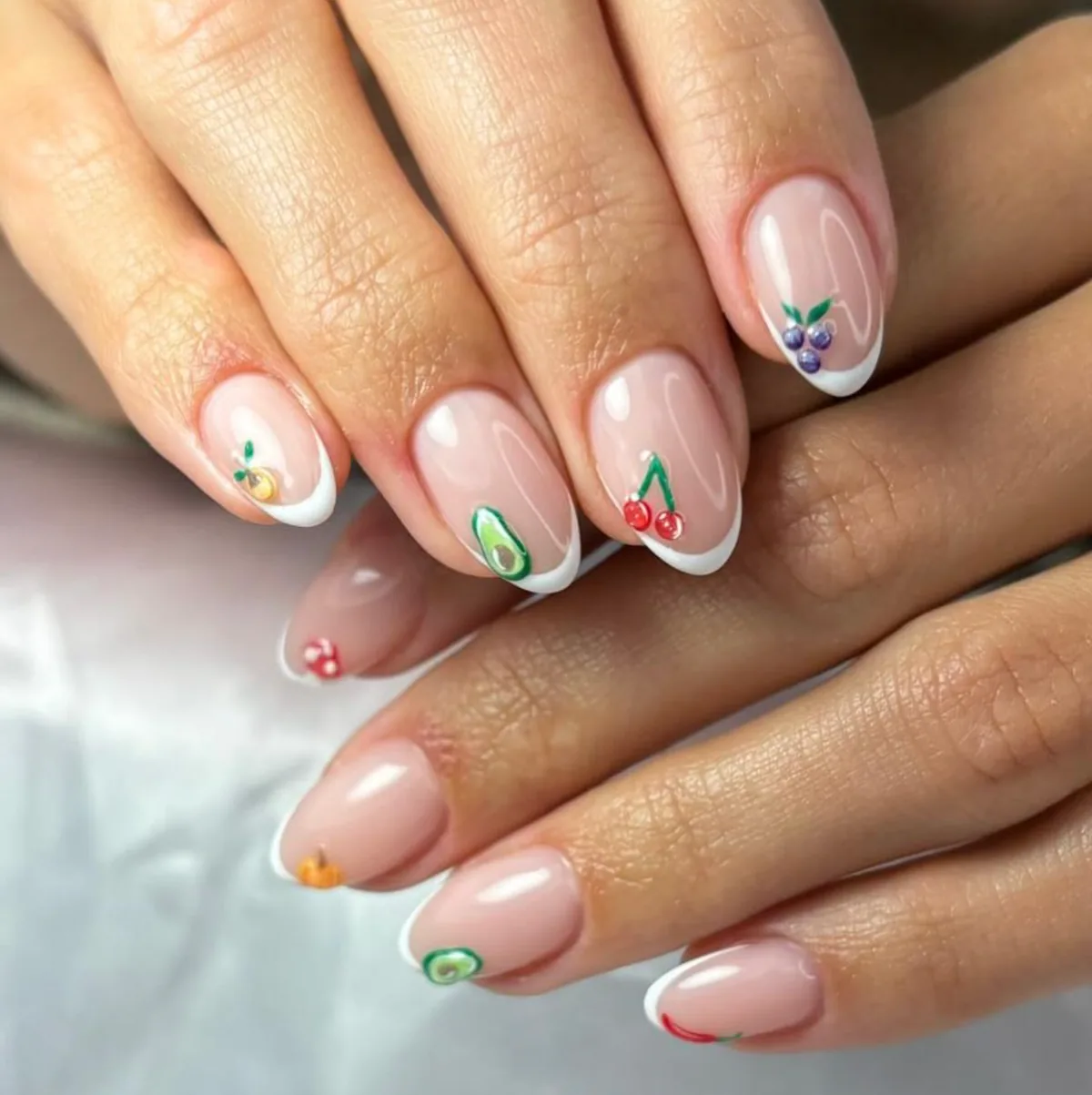 French manicure con pequeños diseños de frutas.