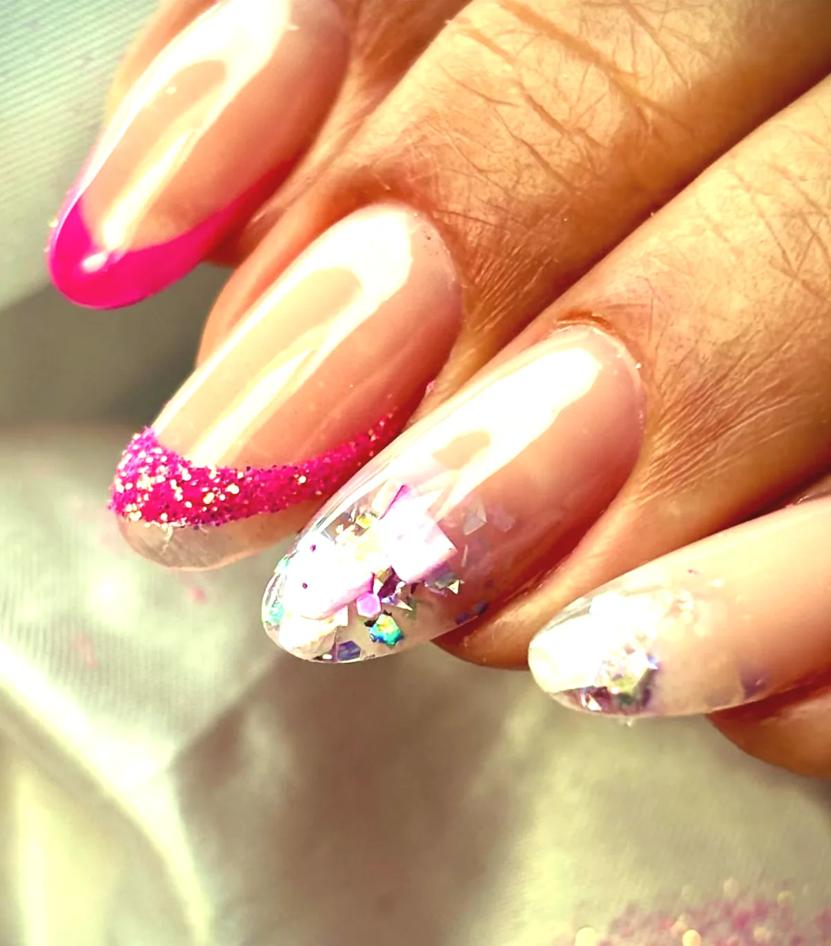 Uñas con puntas fucsias brillantes y detalles holográficos.
