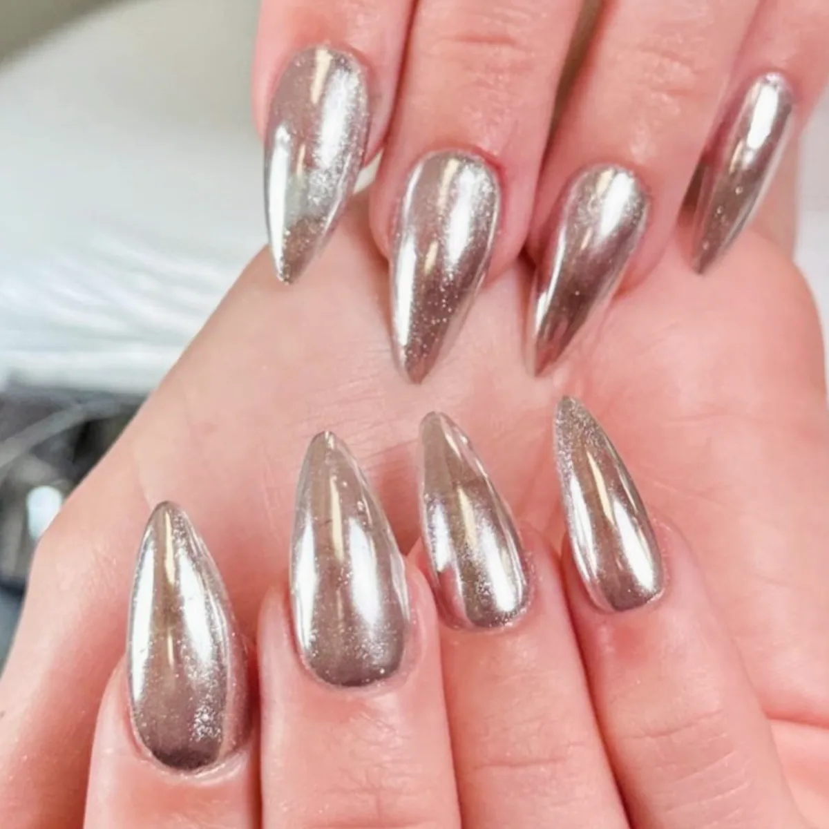 Uñas largas cromadas plateadas con efecto espejo.